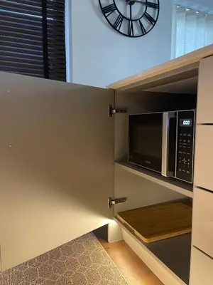 a kitchen with a microwave and a clock on the wall at The Comfort, with Free Parking, Harlow in Harlow