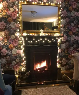 a fireplace with christmas lights and a mirror at Susies Place in Thaxted