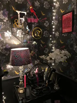 a table with a lamp and a wall with flowers at Susies Place in Thaxted