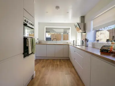 a kitchen with white cabinets and a wooden floor at Farmer's Rest in Ely