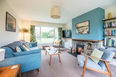 a living room with a blue couch and a fireplace at Telford, Aldeburgh in Aldeburgh