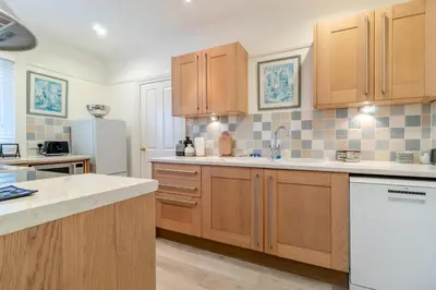 a kitchen with wooden cabinets and a white refrigerator at 2 Bed in Felixstowe oc-m30281 in Felixstowe