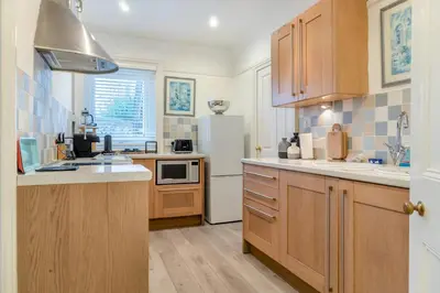 a kitchen with wooden cabinets and a white refrigerator at 2 Bed in Felixstowe oc-m30281 in Felixstowe