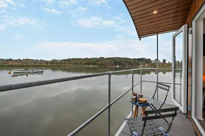 a balcony with a table and a boat on the water at 1 Bed in Woodbridge oc-s30322 in Woodbridge