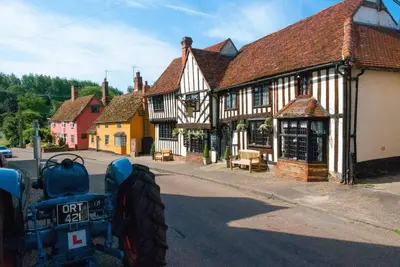an old building with a tractor parked in a street at River House in Kersey