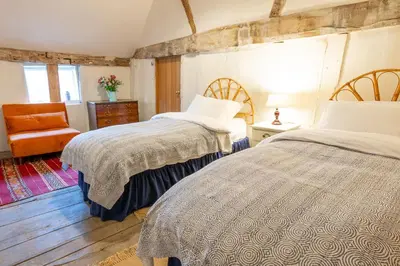 a bedroom with two beds and an orange chair at River House in Kersey