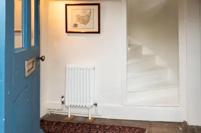 a hallway with a door and a radiator and stairs at River House in Kersey