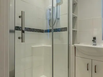 a shower with a glass door next to a sink at Cosy flat in Leigh - Pass the Keys in Southend-on-Sea