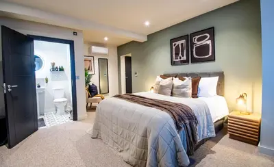 a bedroom with a large bed and a bathroom at Thetford Hive - Premium Self Check-In Aparthotel in Thetford