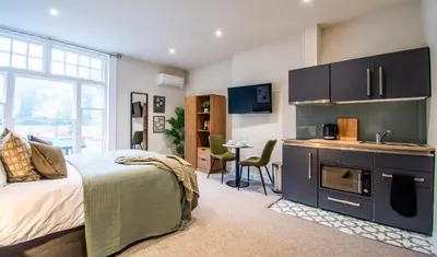 a bedroom with a bed and a kitchen with a sink at Thetford Hive - Premium Self Check-In Aparthotel in Thetford