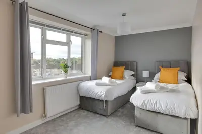 two beds in a room with a window at Homely Apartment in Harlow in Great Parndon