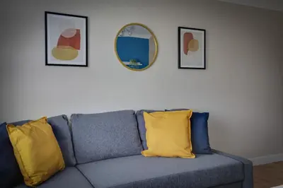 a blue couch with two yellow pillows and a mirror at Homely Apartment in Harlow in Great Parndon