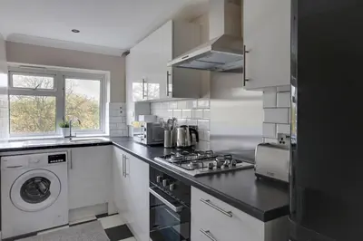 a kitchen with a stove and a washer and dryer at Homely Apartment in Harlow in Great Parndon
