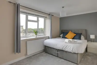 a bedroom with a large bed and a window at Homely Apartment in Harlow in Great Parndon
