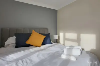 a bedroom with a bed with blue and yellow pillows at Homely Apartment in Harlow in Great Parndon