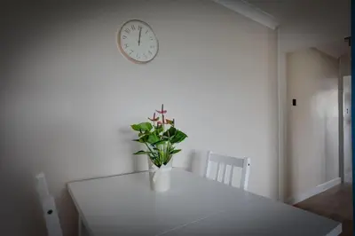 a white table with a vase with a plant on it at Homely Apartment in Harlow in Great Parndon