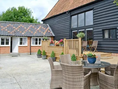 a patio with chairs and a table in front of a house at Rose Farm Barn in Laxfield