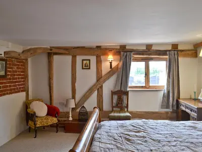 a bedroom with a bed and a desk and a window at Rose Farm Barn in Laxfield