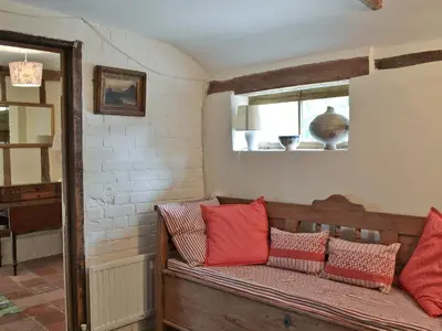 a bench in a room with red pillows on it at Rose Farm Barn in Laxfield
