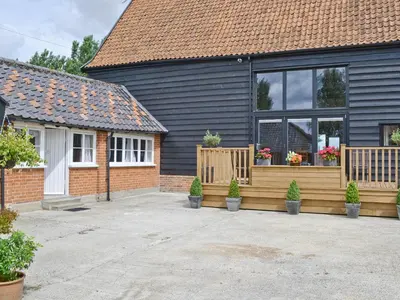 a house with a deck with potted plants on it at Rose Farm Barn in Laxfield