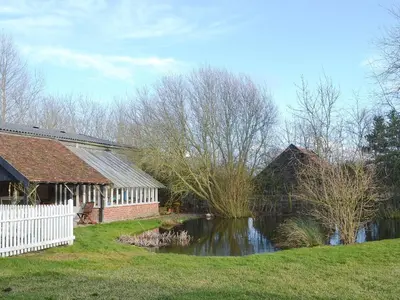 a house and a pond in front of a house at Rose Farm Barn in Laxfield