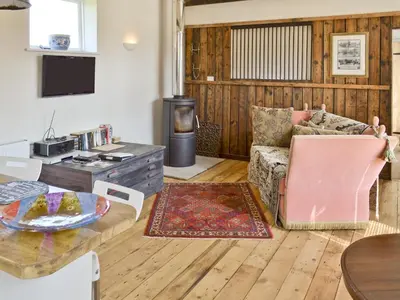 a living room with a couch and a table at Evie Rose Cottage in Elsenham