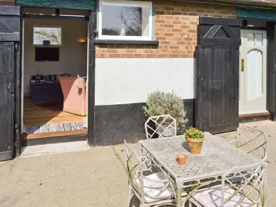 a table and chairs in front of a house at Evie Rose Cottage in Elsenham