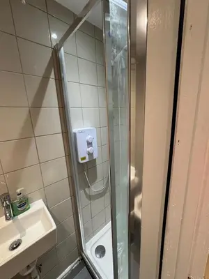 a shower with a glass door next to a sink at M18 Escape in Havering atte Bower