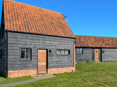 a gray house with a red roof next to two buildings at Sally's Nest - E3042 in Blyford