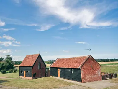 an old barn and a brick building in a field at Carol's Cottage - E3043 in Blyford