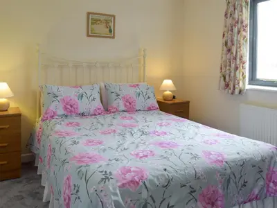 a bedroom with a bed with pink flowers on it at Carol's Cottage - E3043 in Blyford