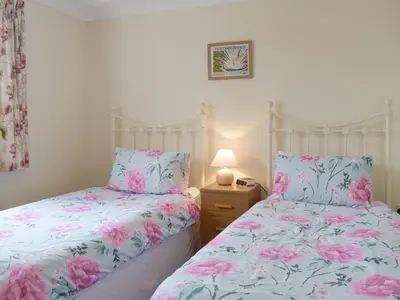 two beds in a bedroom with pink flowers at Carol's Cottage - E3043 in Blyford