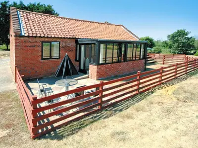 a house with a wooden fence around it at Carol's Cottage - E3043 in Blyford