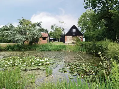 a house and a pond with lilies in front of it at The Stables - E3491 in Saxtead