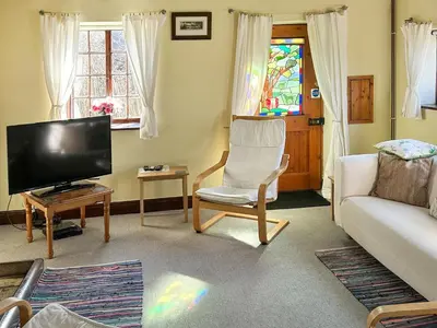a living room with a couch and a tv at Field Cottage in Sudbourne