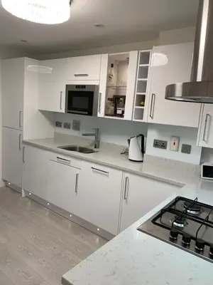 a white kitchen with a sink and a microwave at BYK Homes, Hotels and Suites in Grays Thurrock