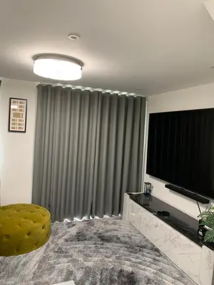 a living room with a large screen television and a chair at BYK Homes, Hotels and Suites in Grays Thurrock