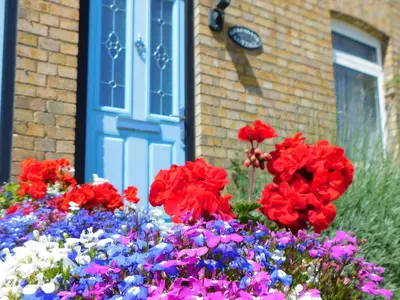 a bunch of flowers in front of a blue door at Greenbank Cottage in Hilgay