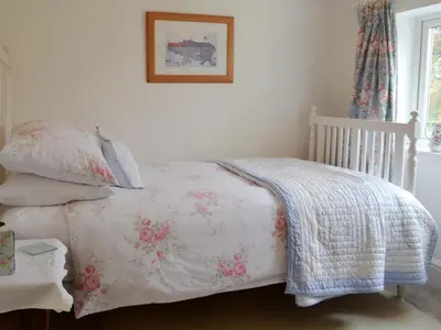 a bedroom with a bed with a blanket and pillows at Greenbank Cottage in Hilgay