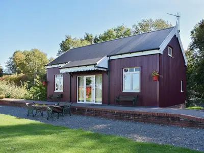 a red house with a table and benches in front of it at The Station - E5336 in Wetheringsett