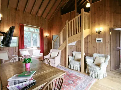 a living room with a wooden staircase and a table and chairs at The Station - E5336 in Wetheringsett