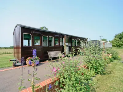 an old train car with a bench and flowers at Railway Carriage One - E5337 in Wetheringsett