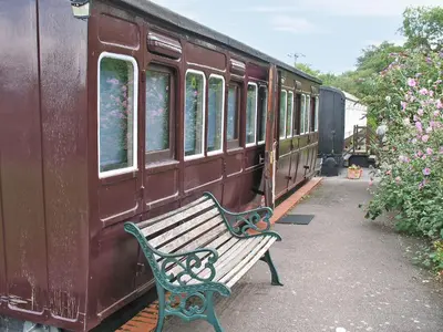 a wooden bench sitting next to a train at Railway Carriage One - E5337 in Wetheringsett