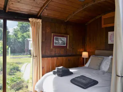 a bed in a wooden room with a window at The Guards Van in Wetheringsett