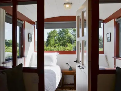 a bedroom with a bed and a window at The Guards Van in Wetheringsett