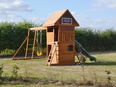 a small wooden playground with a slide and a swing at The Guards Van in Wetheringsett