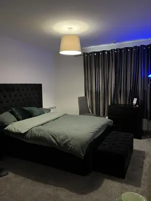 a bedroom with a bed and a lamp and curtains at Serenity-ESE Entire Home in Basildon