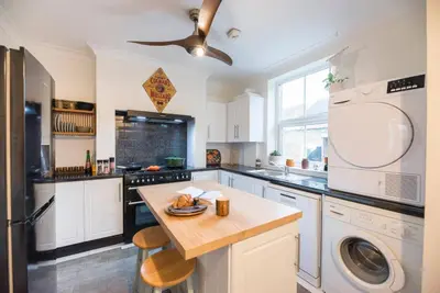 a kitchen with white cabinets and a washer and dryer at Lower Cedars, Saxmundham in Saxmundham