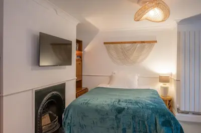a bedroom with a bed with a fireplace and a tv at Lower Cedars, Saxmundham in Saxmundham