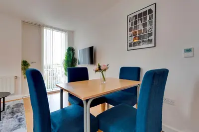 a dining room with a table and blue chairs at 54 Woodpecker Way · Modern apartment near Addenbrookes Free parking Pass the Keys in Cambridge